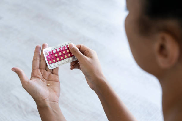 Young woman holding birth control pills stock photo