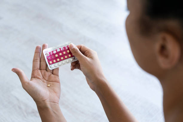 Young woman holding birth control pills Close-up of young woman's hand holding birth control pills birth control pill stock pictures, royalty-free photos & images