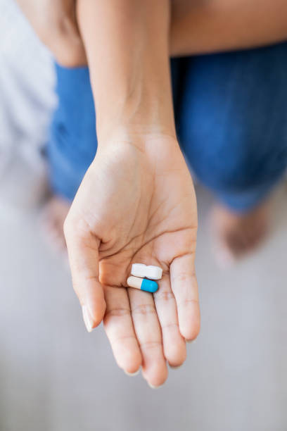 istock Young woman holding pills 1297131217