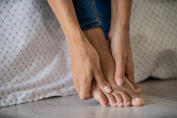 lage sectie van jonge vrouw die haar voet masseert - woman foot stockfoto's en -beelden