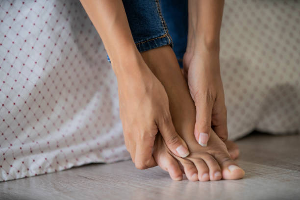 Low section of young woman massaging her foot Close-up of young woman massaging her foot in bedroom feet on feet stock pictures, royalty-free photos & images