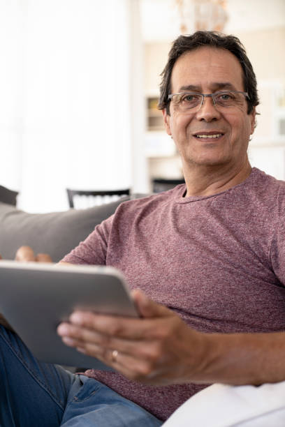 istock Portrait of smiling mature man using digital tablet at home 1297132296