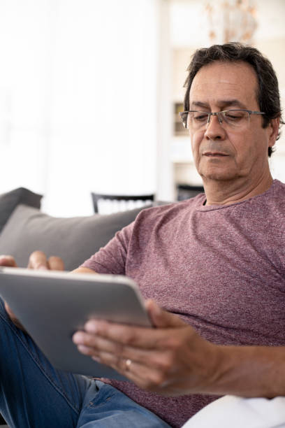istock Serious mature man using digital tablet at home 1297132301