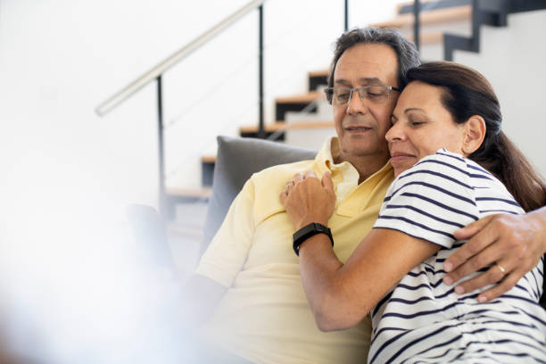 istock Happy mature couple using smartphone on sofa at home 1297132883