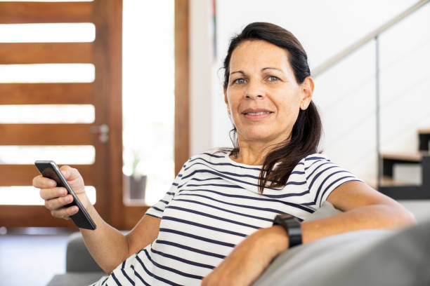 istock Smiling mature woman using smartphone at home 1297132938