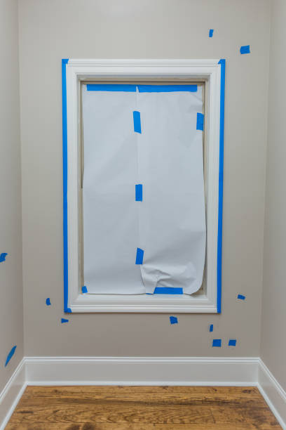 白い紙で覆われた窓に青い画家のテープが貼り付けられている - painting home improvement house painter ストックフォトと画像
