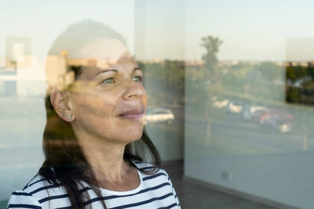 istock Smiling mature woman looking through window 1297133336