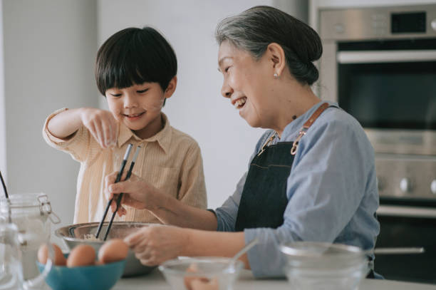 asiatische chinesische 6 jahre alten jungen hilft seiner großmutter zubereiten von essen mit mehl backen an der küchentheke zusammen - 6 7 years fotos stock-fotos und bilder
