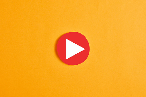 Red round circle with a play button against yellow background.