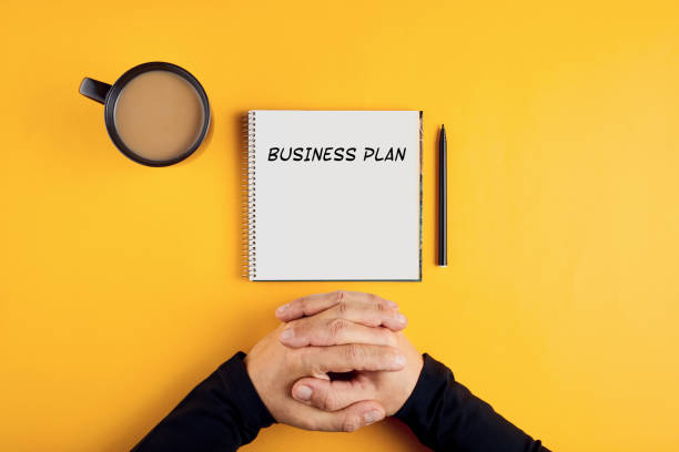 hände eines geschäftsmannes mit spiral-notebook mit business-plan-ideen bereit, in sie geschrieben werden. - business plan stock-fotos und bilder