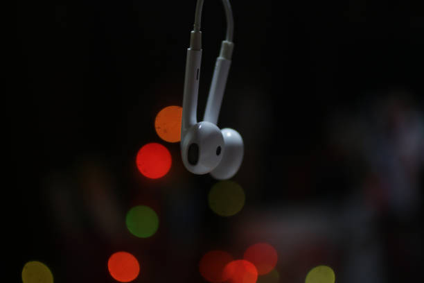 Earphone hanging on dark background with colorful bokeh lights background. Close up of earphone hanging with bokeh light on dark background. Copy space. couple hope sky blue stock pictures, royalty-free photos & images