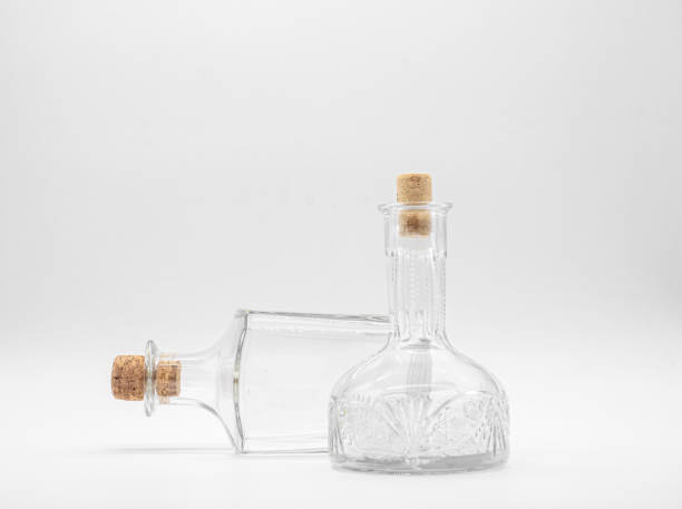 istock Upright empty glass carafe and empty glass bottle lying on its side closed with cork caps isolated on a white background. 1297149964