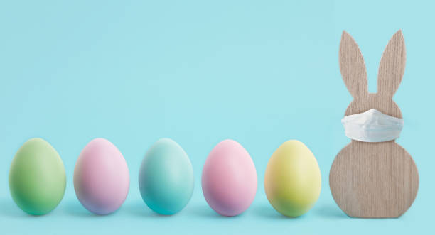 istock Happy Easter banner or border. Coronavirus protection concept for the Easter holidays. Easter rabbit with a protective mask and colorful eggs. Stay at home Covid-19 concept for Easter time with copy space. 1297150713