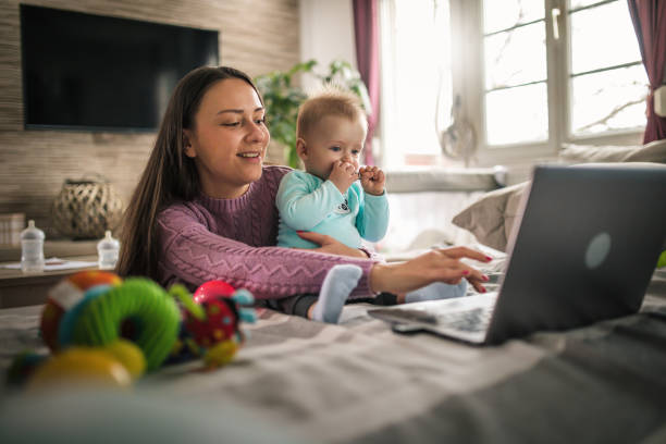 istock Young modern mother with a baby using laptop at home 1297153905