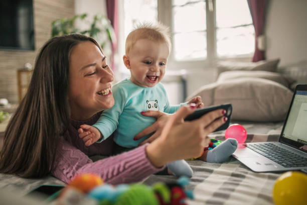 istock Young modern mother with a baby using laptop at home 1297153932