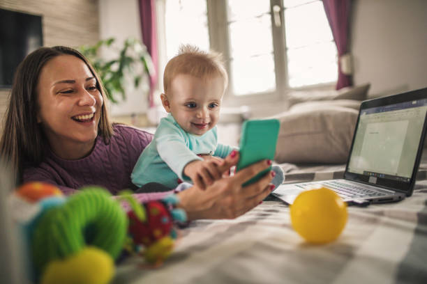 Young modern mother with a baby using laptop at home