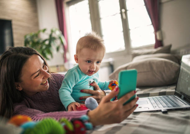 istock Young modern mother with a baby using laptop at home 1297153962