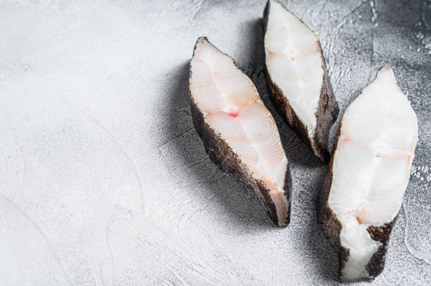 istock Raw fresh steak fish halibut on the stone table. White background. Top view. Copy space 1297155538