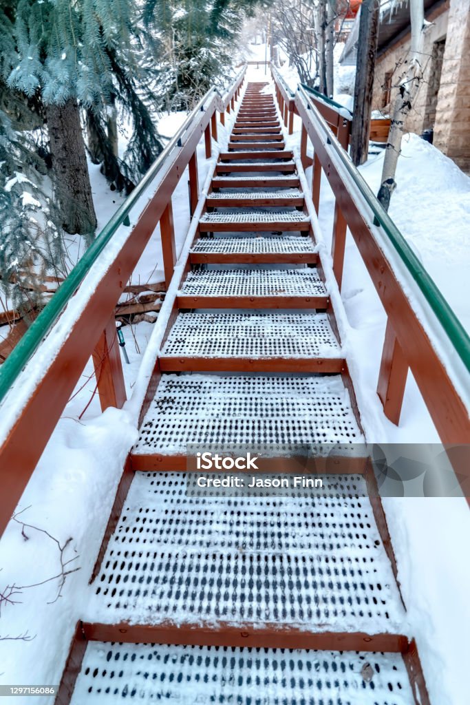 Concentrati sulle scale con battistrada di griglia e corrimano in metallo contro la collina innevata - Foto stock royalty-free di Ambientazione esterna Concentrati sulle scale con battistrada di griglia e corrimano in metallo contro la collina innevata - Foto stock royalty-free di Ambientazione esterna