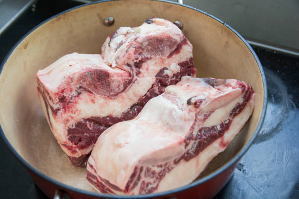 Defrosting two short-ribs meat slices in a red pot stock photo