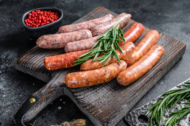istock Assorted raw chorizo sausages on a wooden cutting board. Black background. Top view 1297157175