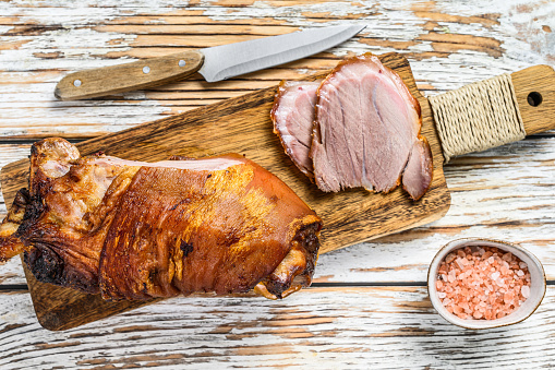 Sliced roasted pork knuckle on a cutting board. wooden background. Top view.