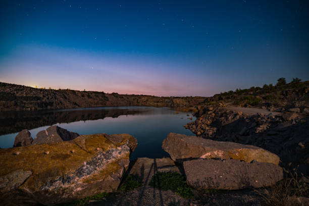 istock Old flooded stone quarry surrounded by stone waste from a mine work against a beautiful night sky 1297158546