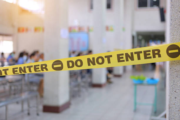 istock Warning yellow tape with text do not enter. Yellow barrier caution tape prohibit access blocking restricted area, due to COVID-19. 1297159199