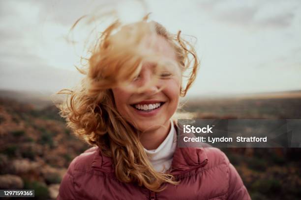 젊은 미소 여자의 초상화는 산에 서 바람이 부는 날에 비행 머리로 부분적으로 덮여 얼굴 평온한 여자 여자에 대한 스톡 사진 및 기타 이미지