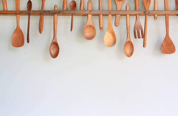 istock Decorative set of wooden kitchen utensils hanging on white wall background. 1297159438