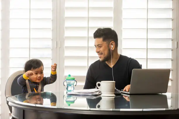 High quality stock photos of a man taking care of his children while teleconferencing with work from his home.