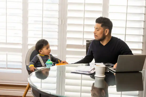 High quality stock photos of a man taking care of his children while teleconferencing with work from his home.