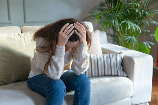 istock Depressed young woman on sofa at home 1297161265