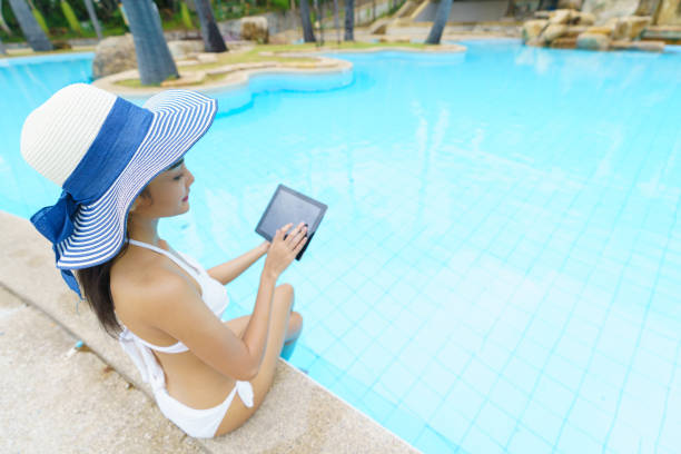 Asian female sitting relax on the pool with digital tablet