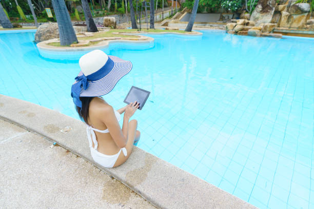 istock Asian female sitting relax on the pool with digital tablet 1297163523