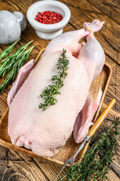 istock Raw whole farm duck with herbs. wooden background. Top view 1297164704
