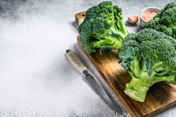 istock Raw green broccoli cabbage on a wooden cutting board. White background. Top view. Copy space 1297165487