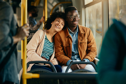 Happy black couple looking through the window while commuting by public transport.