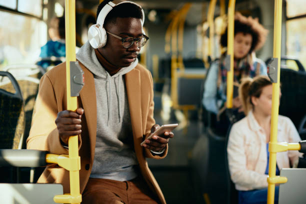istock Young black man with headphones using smart phone while commuting by bus. 1297166180