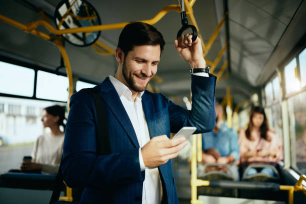 istock Happy male entrepreneur using mobile phone and text messaging while commuting by public bus. 1297166248