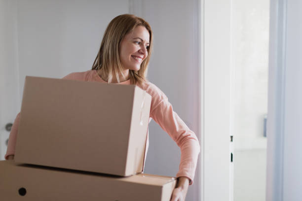 istock Woman carrying cardboard boxes 1297167261