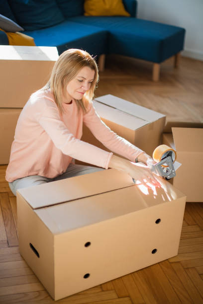 istock Woman closing cardboard box with adhesive tape 1297167325