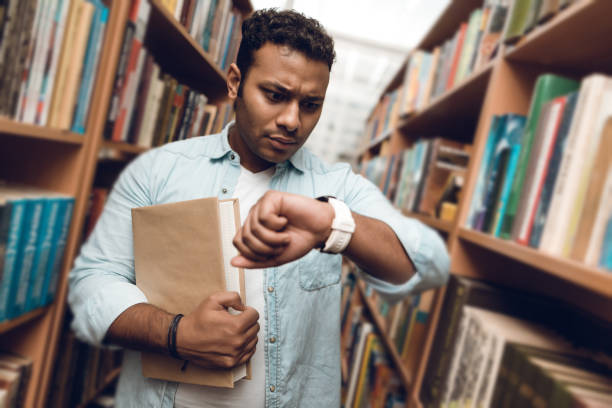 Ethnic indian mixed race student in book aisle of library.