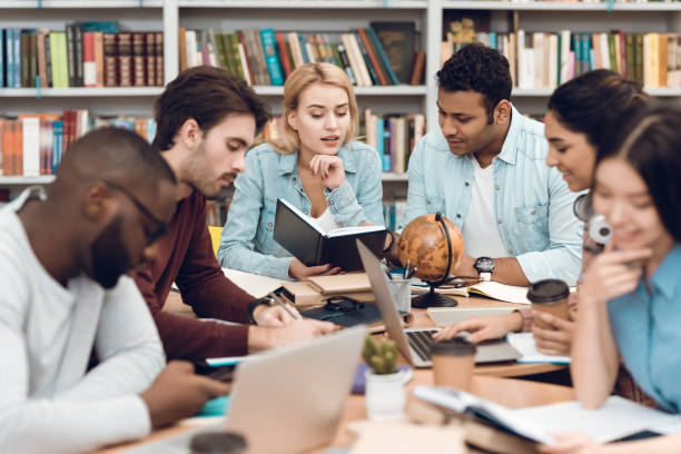 istock Group of ethnic multicultural students in library. Students are talking and reading. 1297168907
