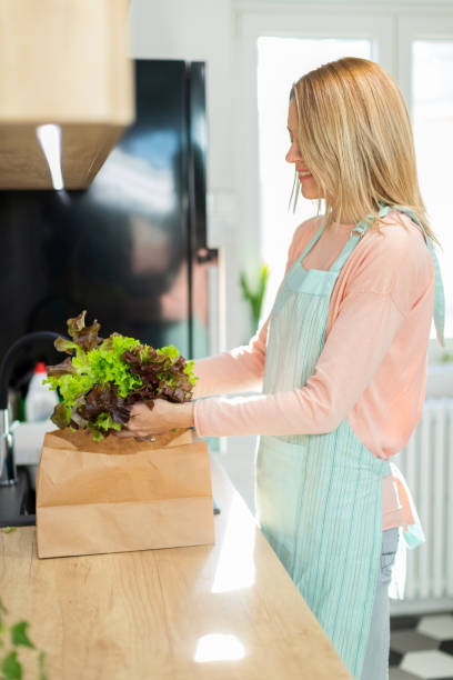 istock Mid adult woman unpacking lettuce 1297168965