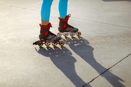 Low section of unrecognizable young woman roller skating on the street, wearing light blue leggings