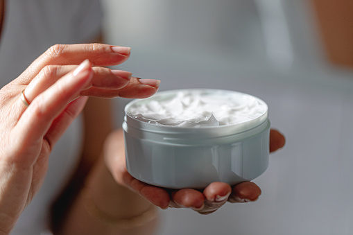 Female hand holding moisturizer, female hand opening moisturizer cosmetic cream