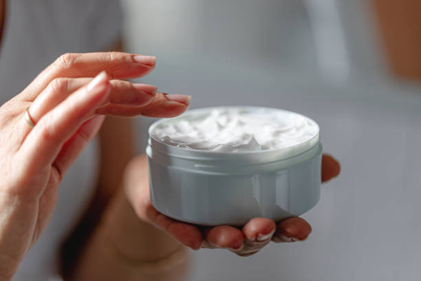 Woman using moisturizing cream for clean and soft skin Close-up of woman using moisturizing cream for clean and soft skin, holding cream jar in hands face cream stock pictures, royalty-free photos & images