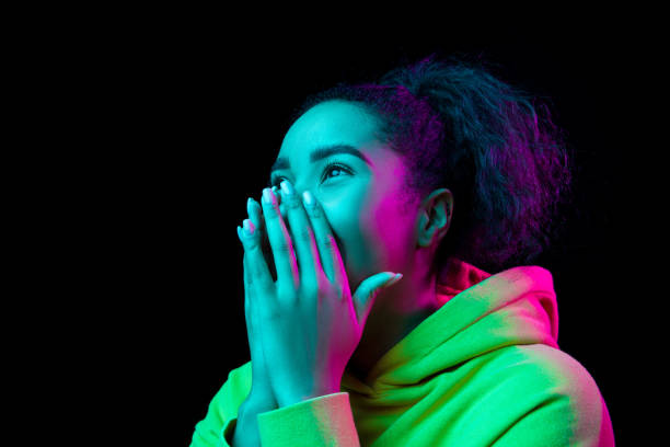 istock African-american woman's portrait isolated on dark studio background in multicolored neon light 1297171682