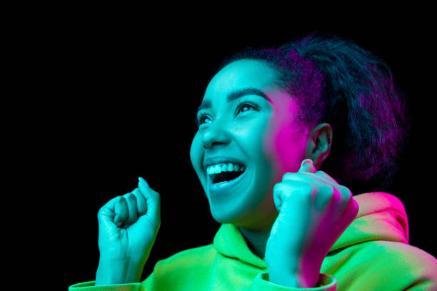 istock African-american woman's portrait isolated on dark studio background in multicolored neon light 1297171685
